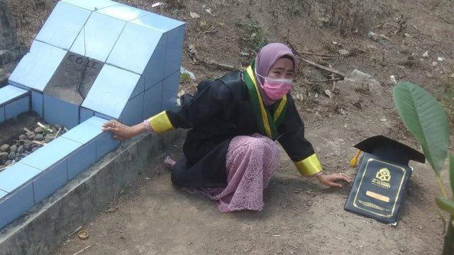 mahasiswi UIN Alauddin Makassar, berpose di depan makam kedua orang tuanya di hari wisuda