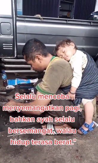 Potret Ayah Kerja di Bengkel Sambil Gendong Anak Tidur